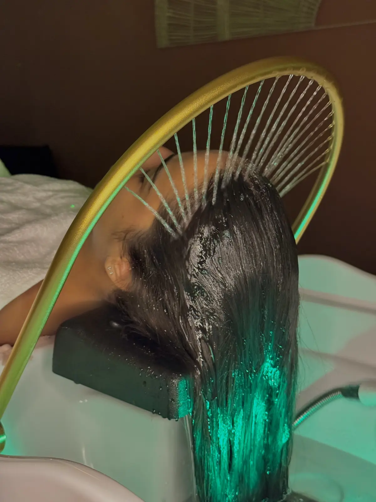 Soin head spa à Marseille : cascade d’eau sur arceau doré au-dessus du bac, lumière émeraude